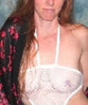 Eine Frau mit roten Haaren zeigt ihre Brüste